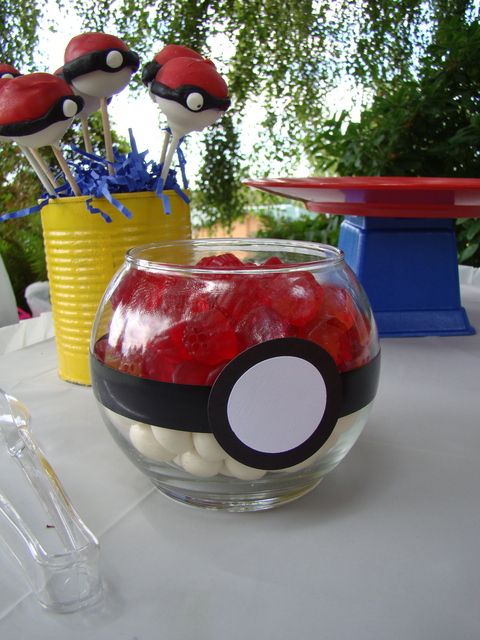 a glass bowl filled with candy sitting on top of a table next to two yellow vases