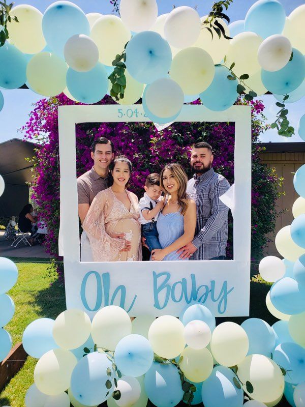 the family is posing for a picture in front of balloons and streamers that read oh baby