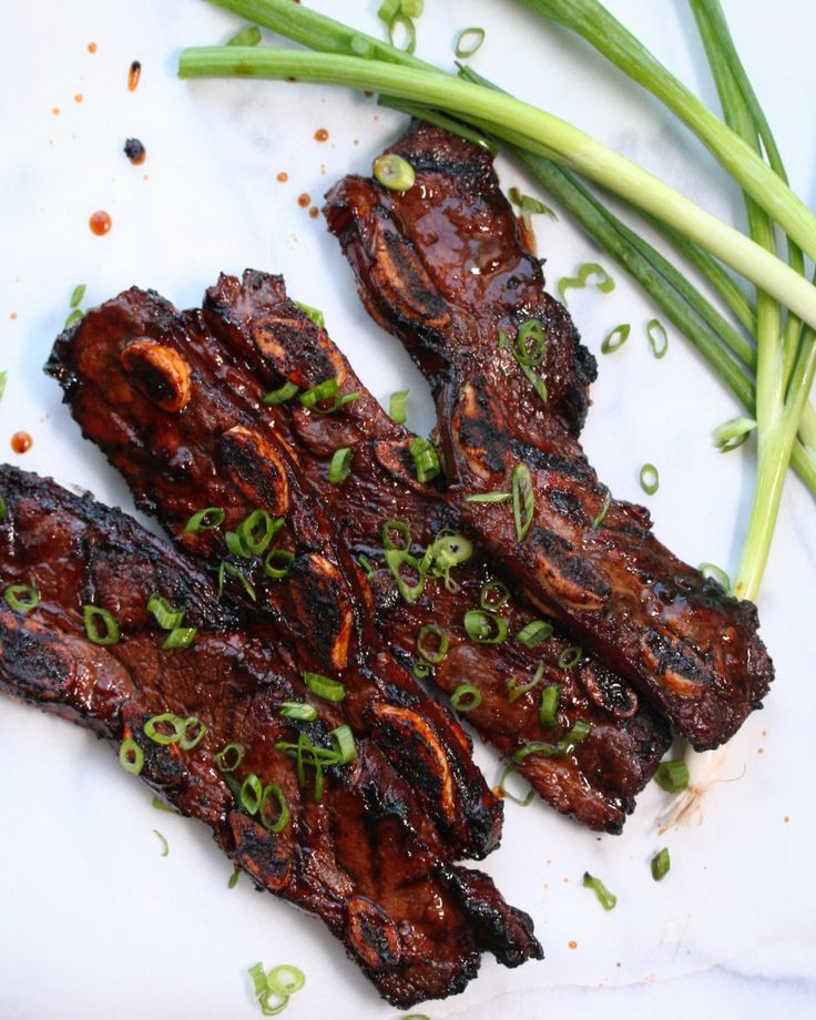 two pieces of meat with green onions on the side