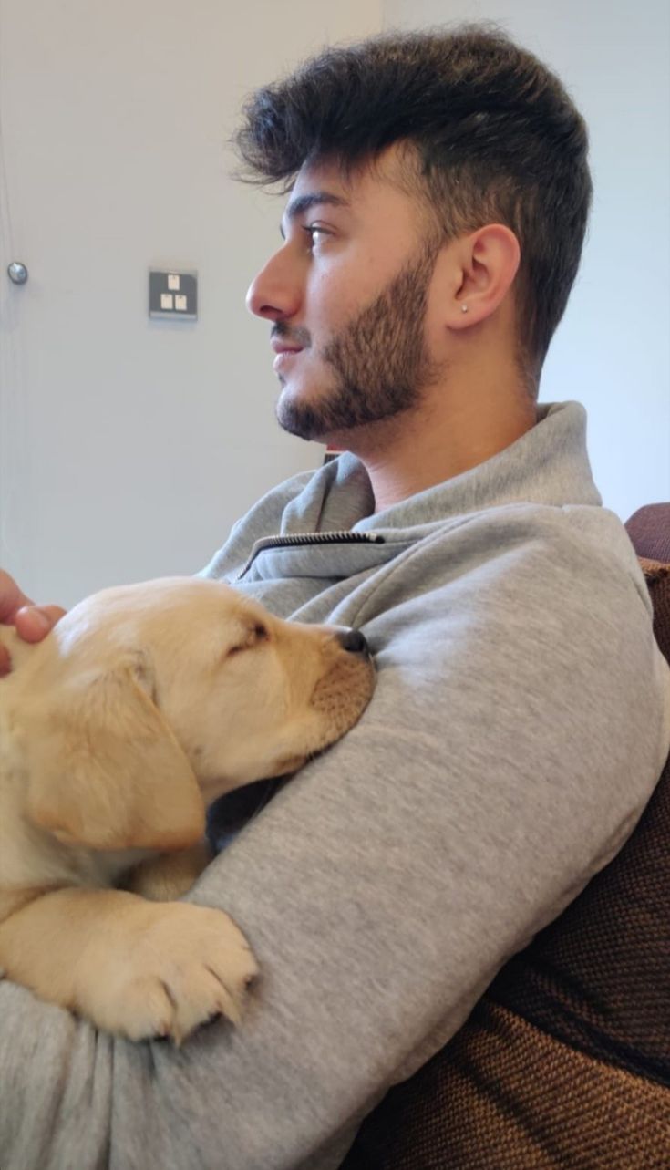 a man sitting on a couch holding a dog