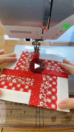 someone is using a sewing machine to sew fabric on a red and white quilt