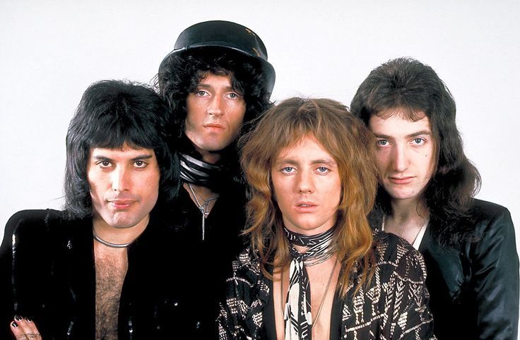 the band kiss posing for a photo in front of a white background with one man wearing a black hat