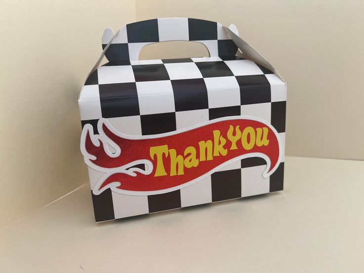 a black and white checkered box with a red thank you sign on the front