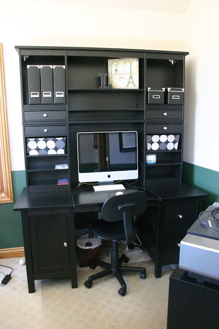 a desk with a computer on top of it in front of a wall mounted clock