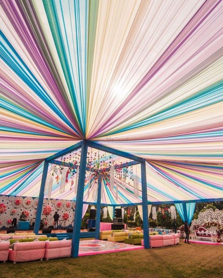 the inside of a tent decorated with multicolored ribbons and chandelier hanging from it's ceiling