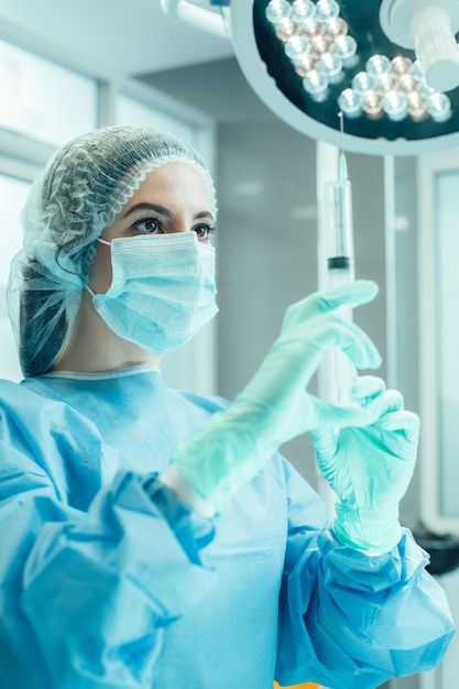 a woman in scrubs and gloves holding up a syosht to the camera