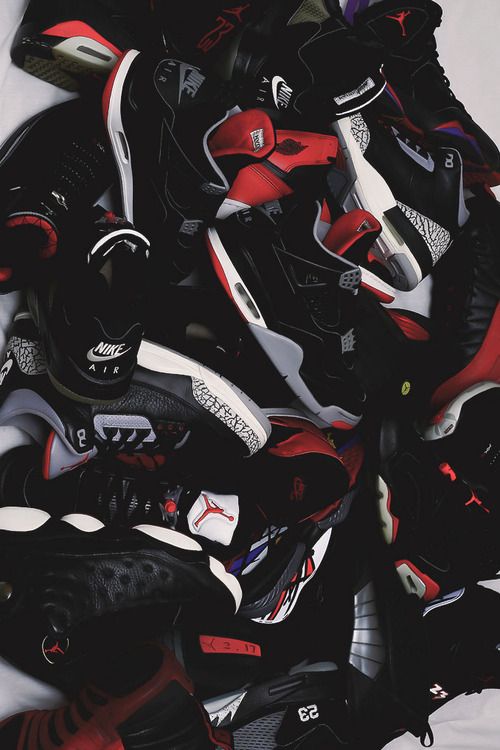 a pile of black, red and white shoes sitting on top of eachother