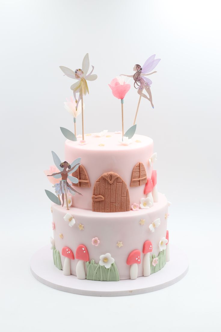 a three tiered cake decorated with pink frosting and fairy figurines on top