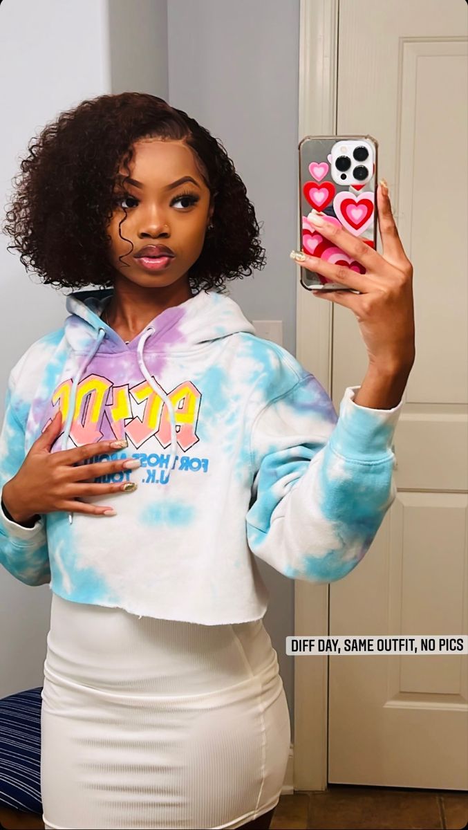 a woman in a tie dye hoodie holding up a cell phone with hearts on it