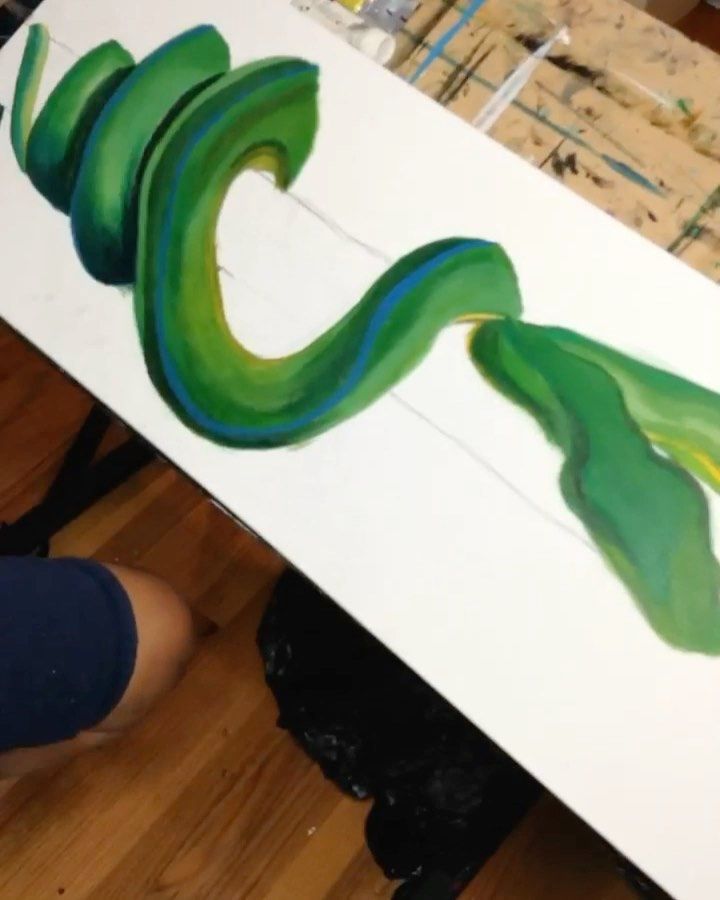 a person is holding up a piece of art with green and blue paint on it