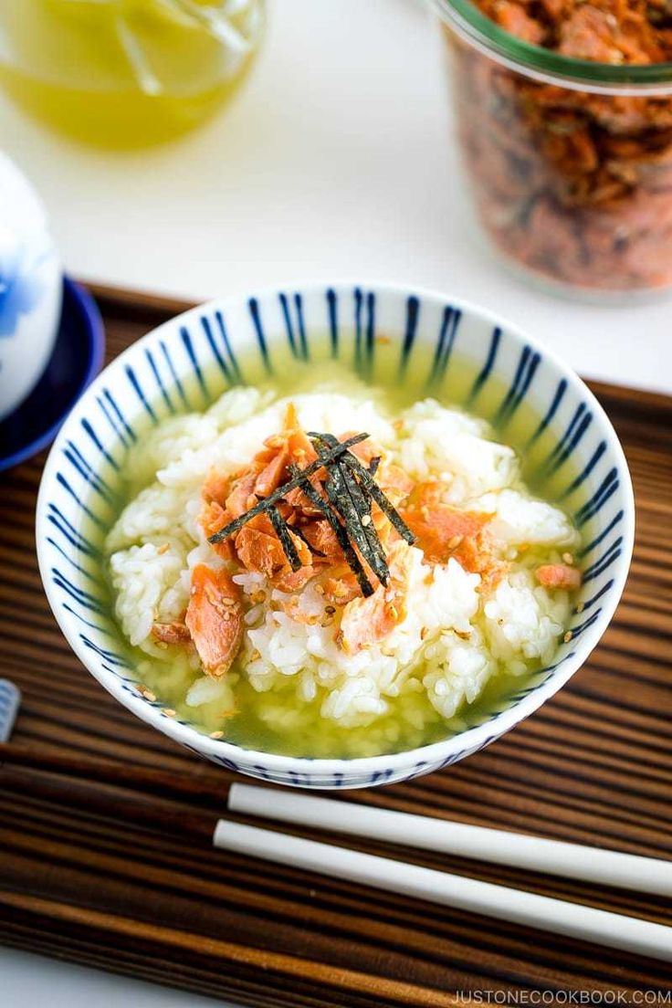 a bowl filled with rice and vegetables next to chopsticks on a wooden tray