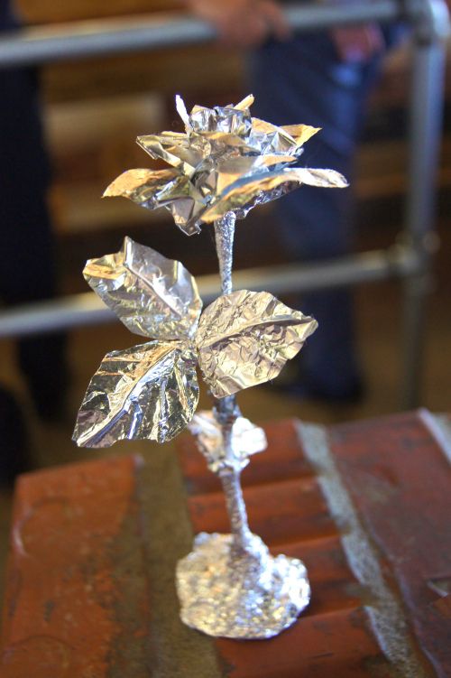 a silver flower sculpture sitting on top of a wooden table