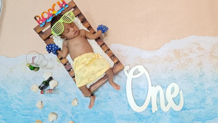 a baby laying in a beach chair with the word one painted on it's side