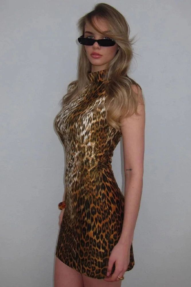 a woman in a leopard print dress with sunglasses on her head and one hand on her hip