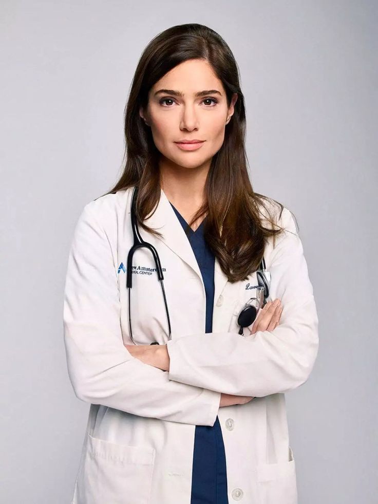 a woman in a white lab coat standing with her arms crossed and looking at the camera