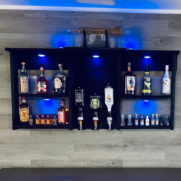 a bar with liquor bottles and glasses on the back wall, lit up by blue lights