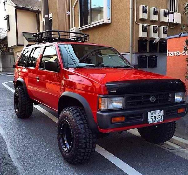 a red pick up truck parked on the side of a road next to a building