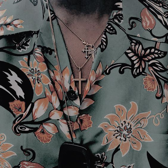 a close up of a person wearing a shirt with flowers on it and a cross in the middle