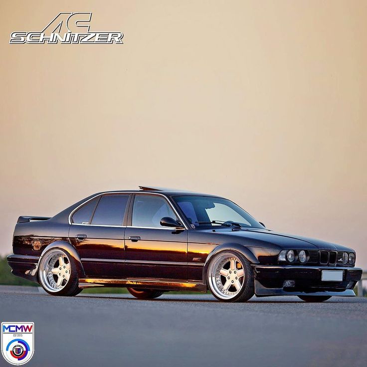 an image of a black car parked on the side of the road in front of a wall