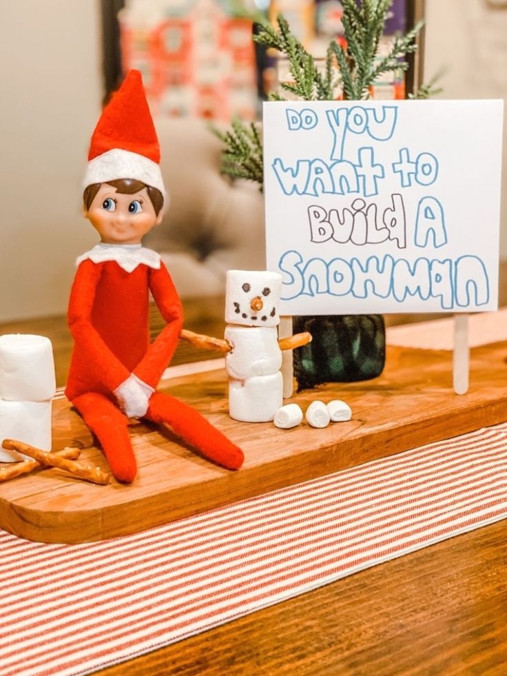 an elf sitting on top of a wooden table next to a sign