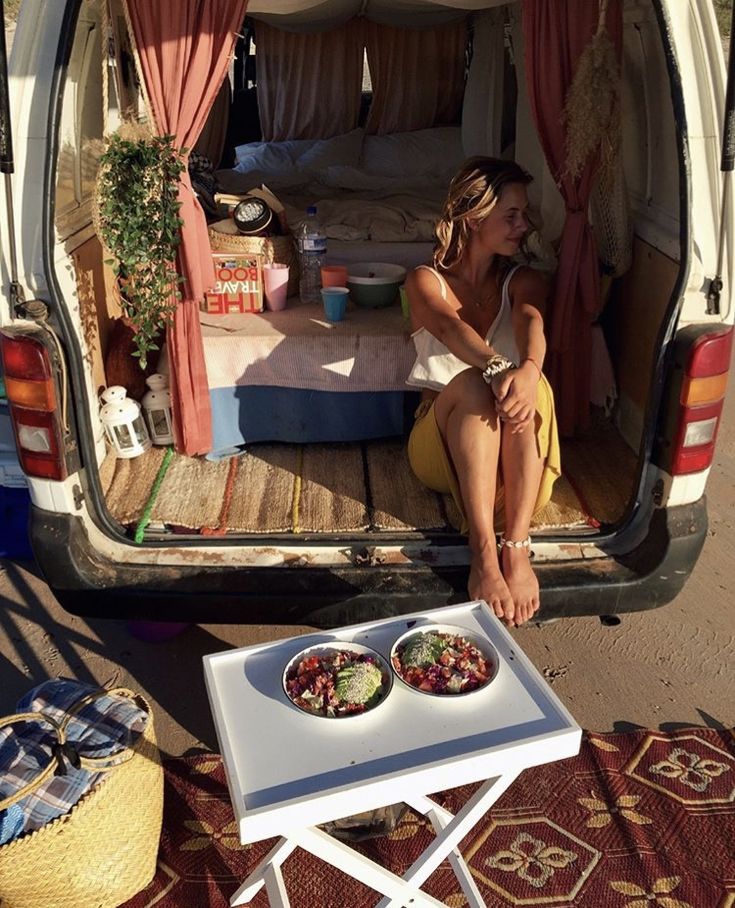 a woman sitting in the back of a van eating food