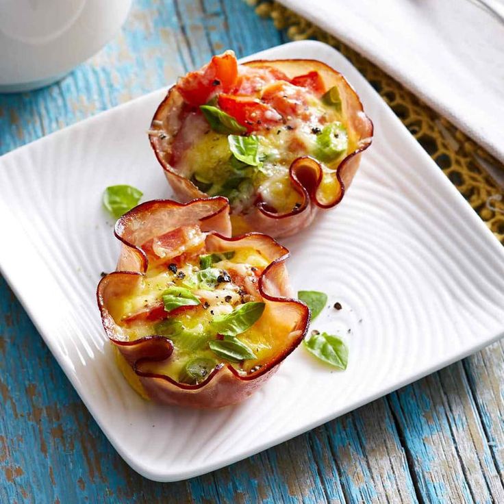 three appetizers on a white plate sitting on a blue wooden table next to a cup of coffee