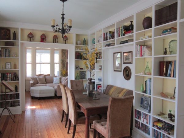 a dining room table with chairs and bookshelves