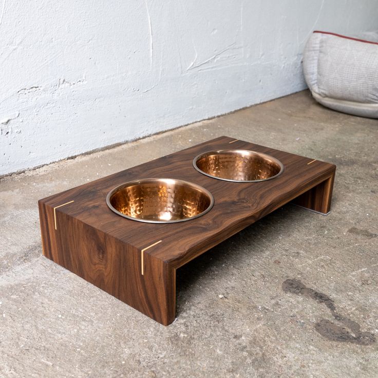 two metal bowls sit on top of a wooden table that is made out of wood