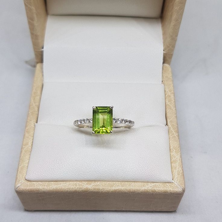 14k solid white gold natural AAA quality emerald cut rectangular shaped peridot gemstone and natural round brilliant cut shaped diamonds gemstones ring. 1. The weight of natural peridot gemstone used in the ring =1.40 cts. 2. The weight of natural diamonds gemstones used in the ring =0.20 cts. 3. The weight of 14k solid white gold used in the ring =2.350 grms. 4. The design of the ring is very very nice and beautiful. 5. The peridot is the birthstone for the people born in the month of August. 6 Green Topaz Ring In Sterling Silver, Green Topaz Sterling Silver Ring In Fine Jewelry Style, Green Topaz Sterling Silver Ring, Green Emerald Cut Topaz Ring With Prong Setting, Fine Jewelry Green Topaz Ring Emerald Cut, Green Peridot Birthstone Ring With Prong Setting, Emerald Cut Peridot Ring For May Birthstone, Green Sapphire Ring With Sterling Silver, Green Topaz Emerald-cut Ring Fine Jewelry