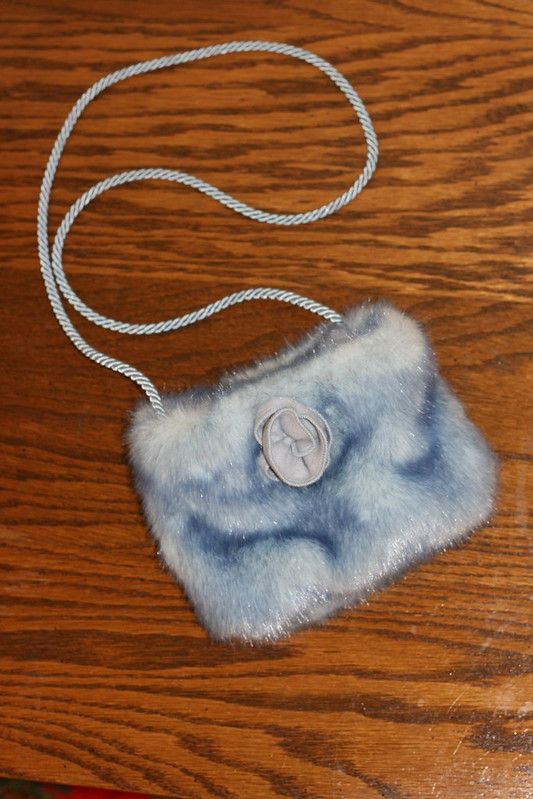 a small blue purse sitting on top of a wooden table next to a white cord