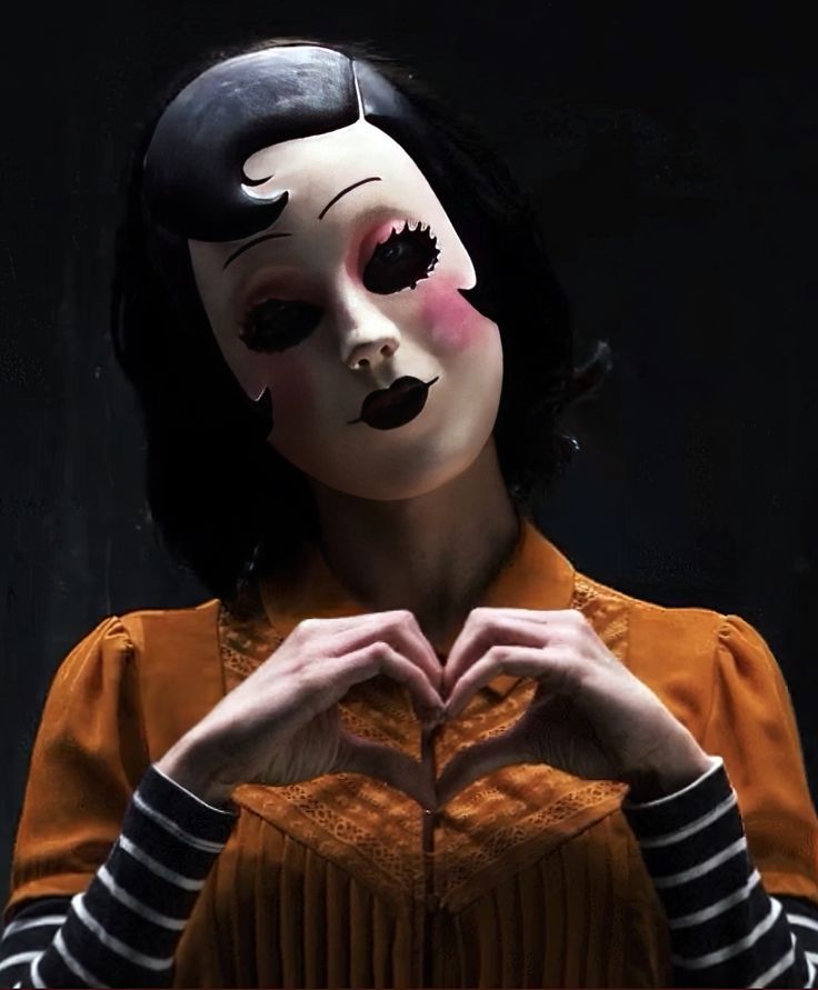 a woman wearing a mask making a heart with her hands