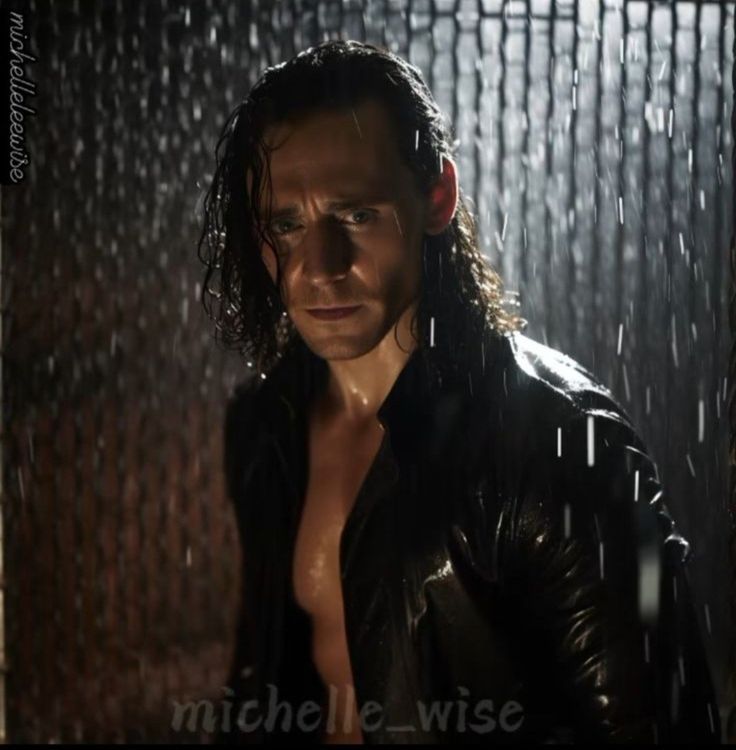 a shirtless man standing in the rain with his jacket open and looking off to the side