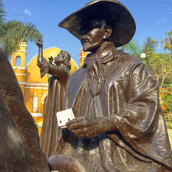 a statue of a man in a hat and robe holding a book next to an elephant