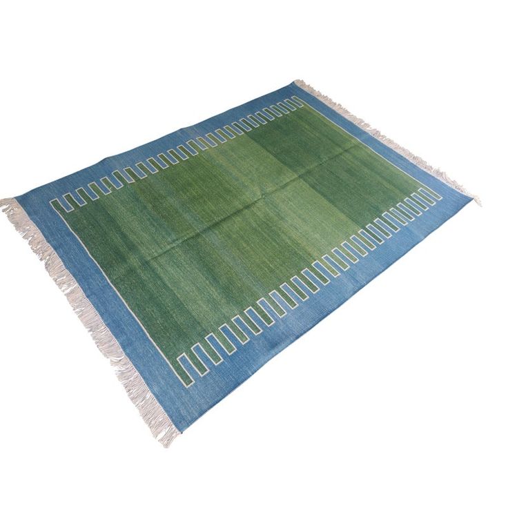 a blue and green rug with fringes on the bottom, in front of a white background