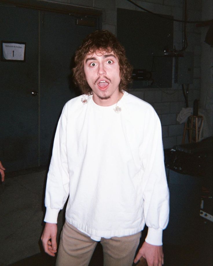 a man making a surprised face while standing in a room