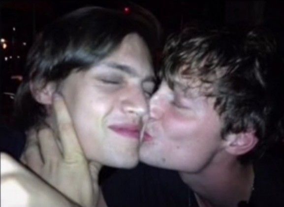 two young men kissing each other in the dark