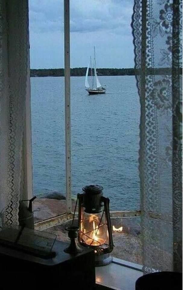 a lantern sitting on top of a window sill next to a boat in the water