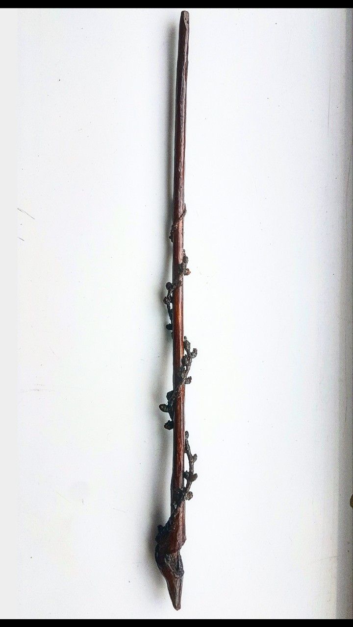 an old wooden stick is hanging on the wall with some metal spikes attached to it