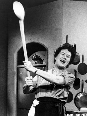 a woman holding a large wooden baseball bat in her hand while standing next to a stove