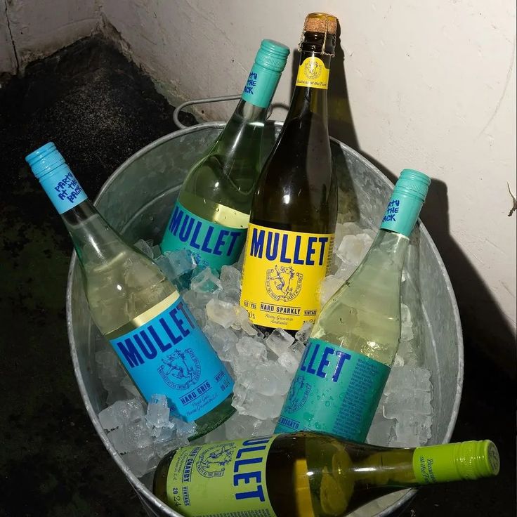 six bottles of miller's ice water in an ice bucket on top of crushed ice