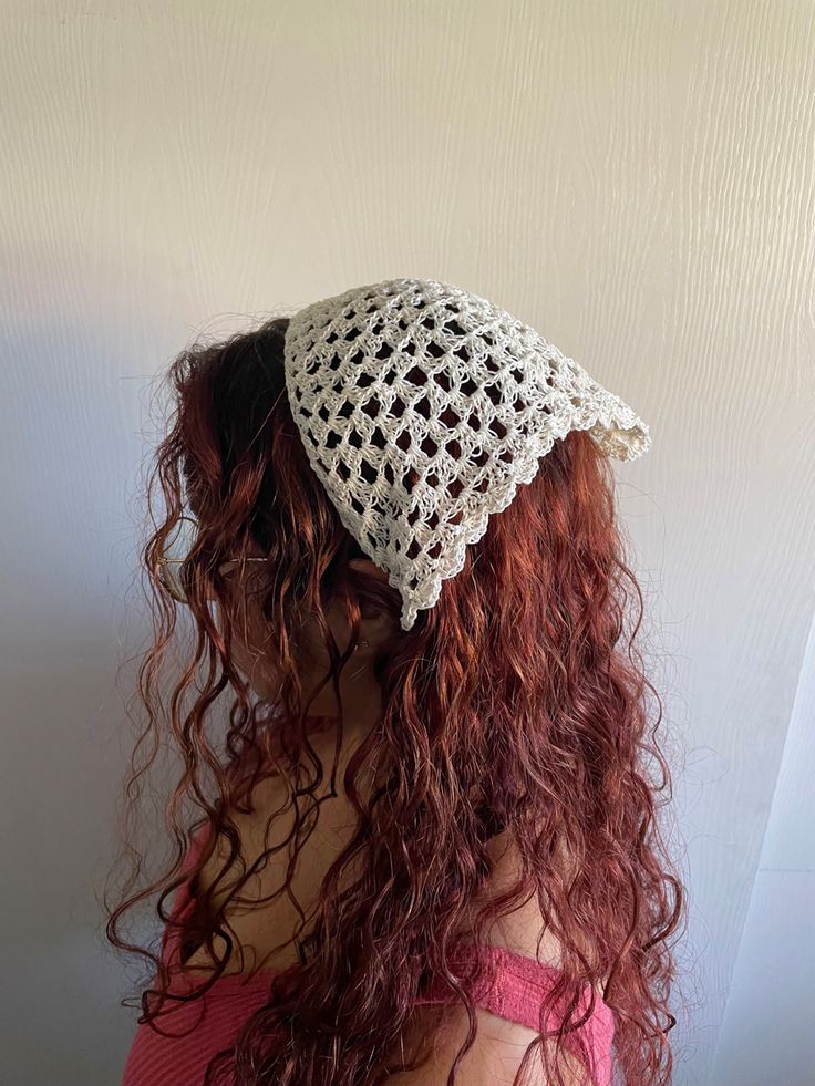 a woman with long red hair wearing a white crochet hat on her head