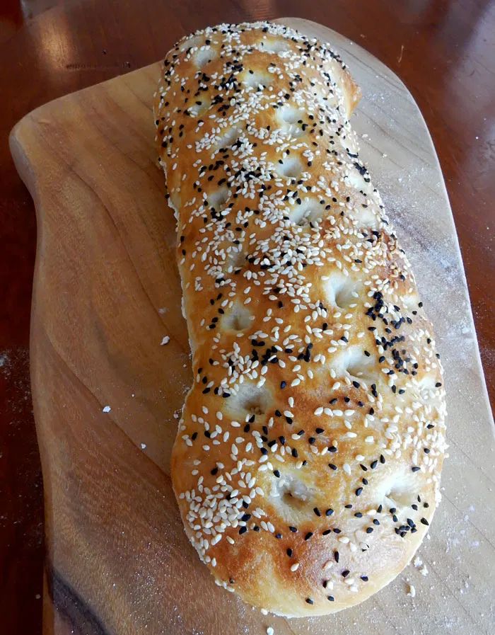 a bagel with sesame seeds is on a cutting board