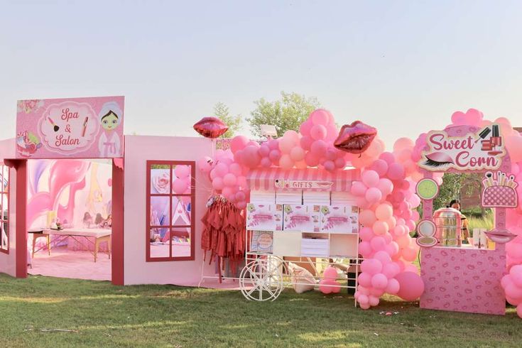 a pink ice cream stand with balloons on the front and side walls, decorated in pink