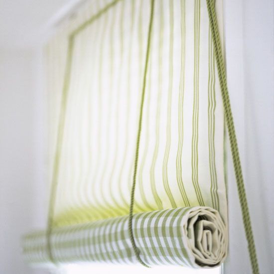 a green and white striped curtain hanging from the side of a window with a rope attached to it