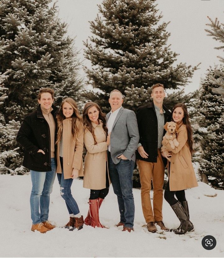 a group of people standing next to each other in front of some snow covered trees