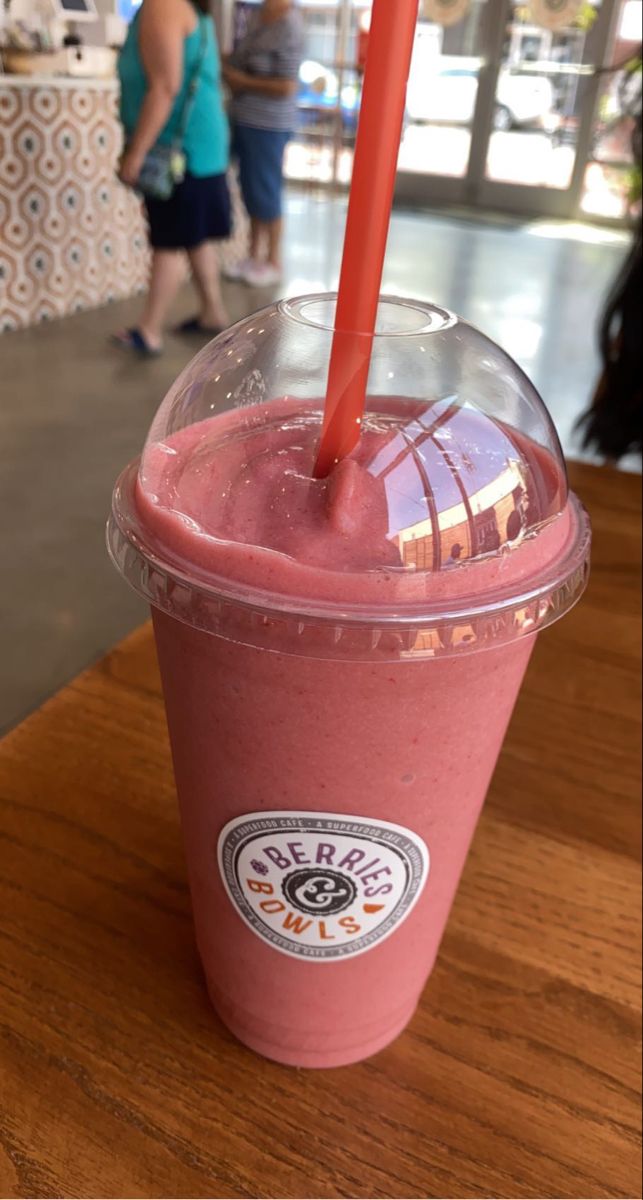 a pink smoothie in a plastic cup with a red straw