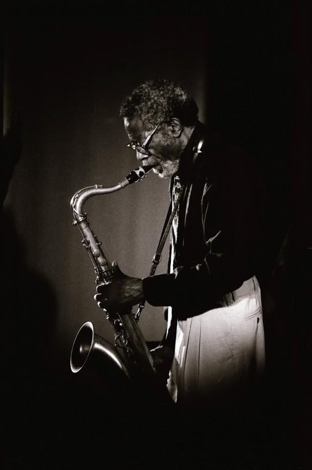 black and white photograph of a man playing a saxophone in the dark with his eyes closed