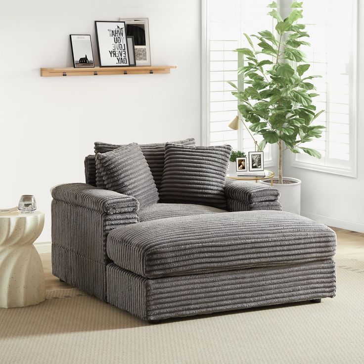 a living room with a large gray chair and white vases on the side table