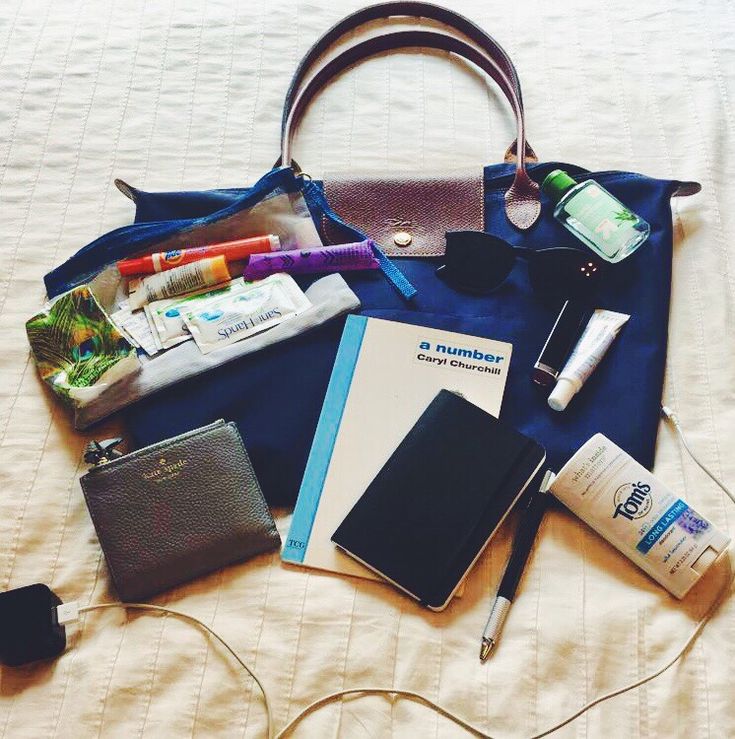 an assortment of personal items laid out on a bed with a purse and other items