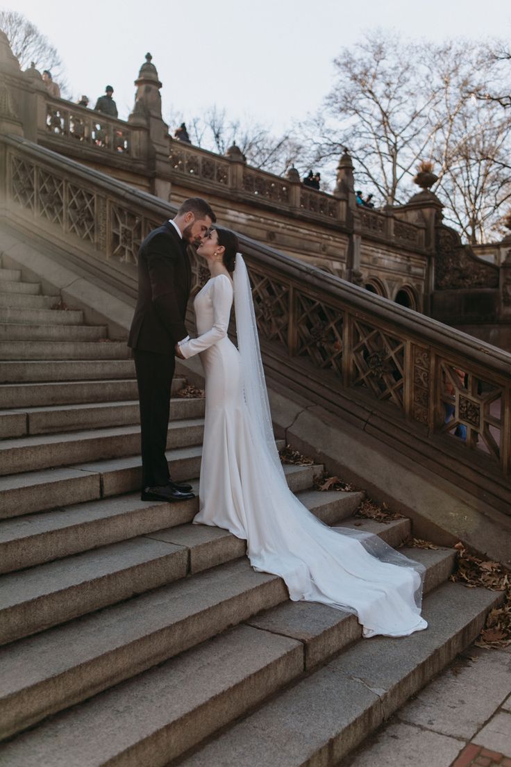 a bride and groom kissing on the steps